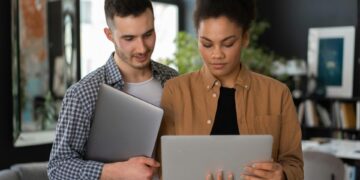 Man and woman holding laptops